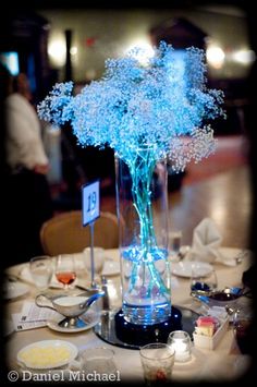 a vase filled with blue flowers sitting on top of a white tablecloth covered table