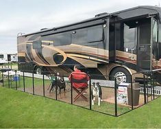 a large motor home sitting on top of a lush green field next to a dog