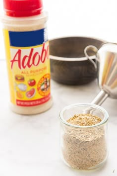 spices and seasoning are sitting on a counter next to a measuring spoon, bowl with food in it