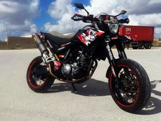 a black and red motorcycle parked on top of a parking lot next to a truck