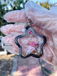 a hand holding a small star shaped object with flowers on it's side and beads in the middle