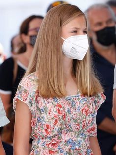 a woman wearing a face mask while standing in front of a group of other people