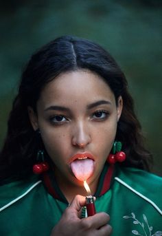 a young woman holding a lit candle in her mouth