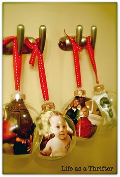 three christmas ornaments hanging on the wall with red ribbon and photo ornament attached to them