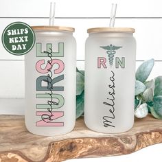 two personalized tumblers sitting on top of a wooden table next to a plant