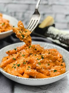 a fork full of pasta with sauce and parmesan cheese on the side in a white bowl