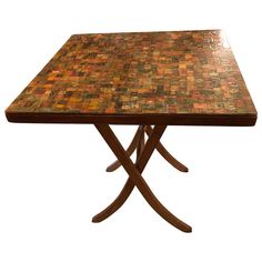 a wooden table with multicolored tiles on it's top and cross legs