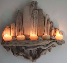 candles are lit on a shelf made out of driftwood