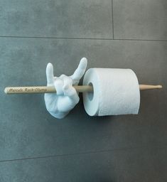 a hand holding a roll of toilet paper with a wooden stick sticking out of it