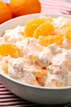 a bowl filled with oranges on top of a red and white striped table cloth