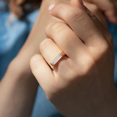 a woman's hand with a diamond ring on her left wrist and the other hand holding an object