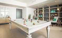 a pool table in the middle of a room with shelves and chairs on either side