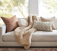 a couch with several pillows on it in front of a window