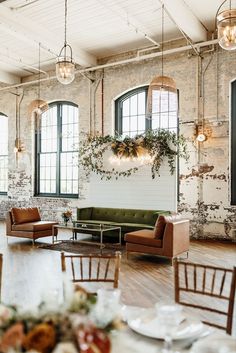 a room filled with furniture and windows next to a wall covered in hanging plants on the walls