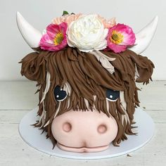 a cake shaped like a cow with flowers on its head