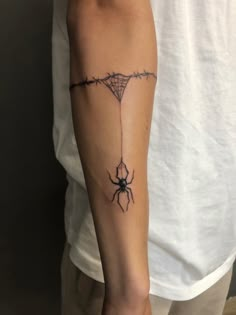 a man with a spider tattoo on his arm, holding onto a barbwire