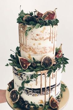 a three tiered cake decorated with figs and greenery