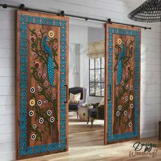 two wooden doors decorated with blue and green designs, one is open to the living room