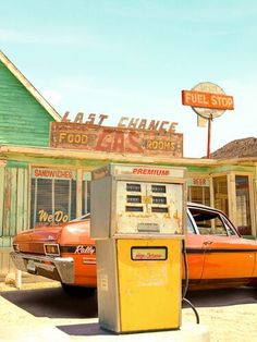 an old gas station with two cars parked in front