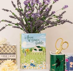 purple flowers are in a vase next to books and scissors