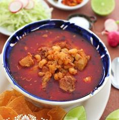 a bowl of soup on a plate with tortilla chips and other food items