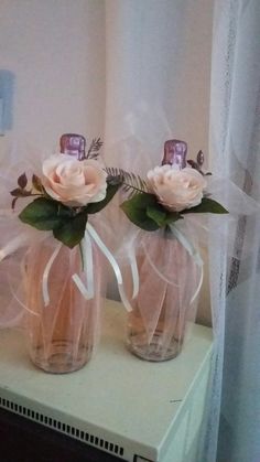 two vases with flowers are sitting on a shelf