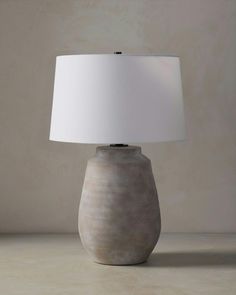 a table lamp with a white shade on it's base, sitting on a counter