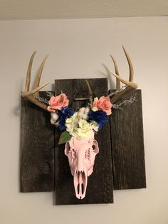 a deer's skull with flowers and antlers mounted on a wall