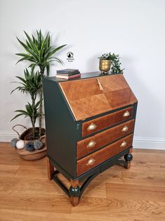 an old fashioned wooden desk with two drawers and a potted plant next to it