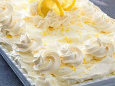 a close up of a cake with lemons on top and frosting around the edges