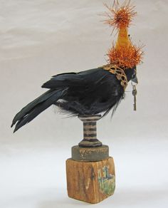 a black bird sitting on top of a wooden block with feathers in it's beak