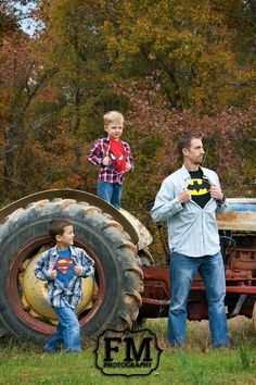 a man and two boys standing in front of an old tractor