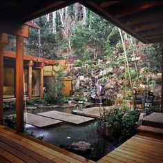 an outdoor garden with a pond and wooden decking, surrounded by rocks and trees