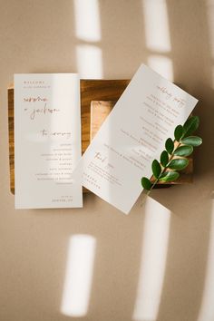 the wedding stationery is laid out on a wooden tray