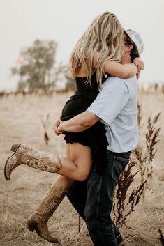 a man and woman hugging in the middle of a field