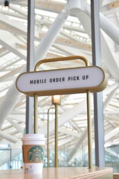 a starbucks cup sitting on top of a counter next to a sign that says mobile order pick up