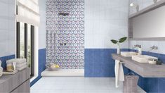 a bathroom with blue and white tiles on the walls, two sinks and a bathtub