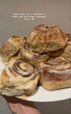 a person holding a plate with cinnamon rolls on it