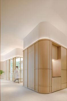 a person walking in an empty room with white walls and flooring on the other side