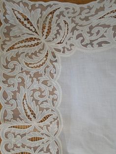 the white lace is laying on top of the table cloth, which has an intricate design