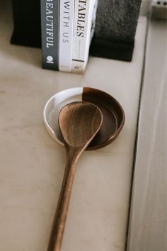 a wooden spoon sitting on top of a white counter next to a book shelf with books