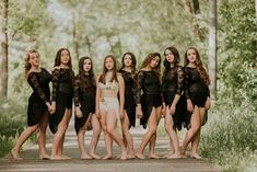 a group of young women standing next to each other in front of trees and bushes