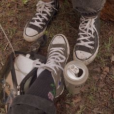 two people standing next to each other with their shoes on and one holding a can