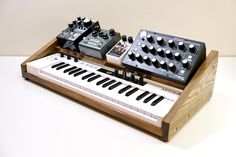 an electronic keyboard sitting on top of a wooden stand next to two other musical instruments