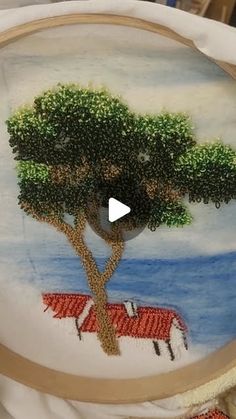 an embroidery project is being displayed on a white cloth with a tree in the middle