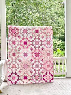 a pink and white quilt sitting on top of a porch