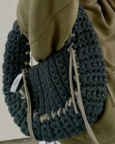 a person holding a crocheted purse on their back