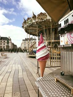 an ice cream cone with pink and white icing sitting on top of a wooden bench