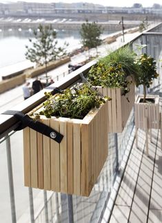 some plants are growing in wooden planters on a balcony