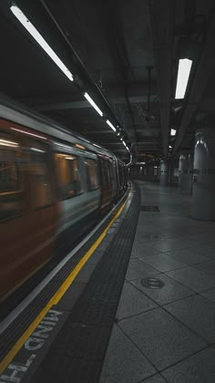 the train is moving fast through the subway station with its lights on and no people in it